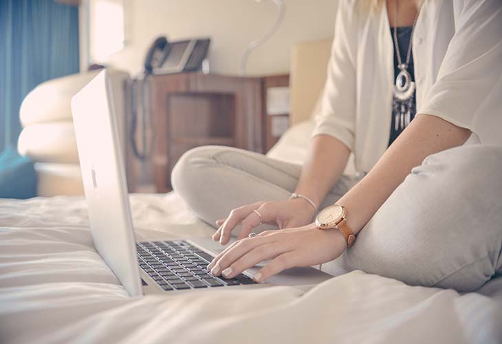 Woman on laptop in bedroom